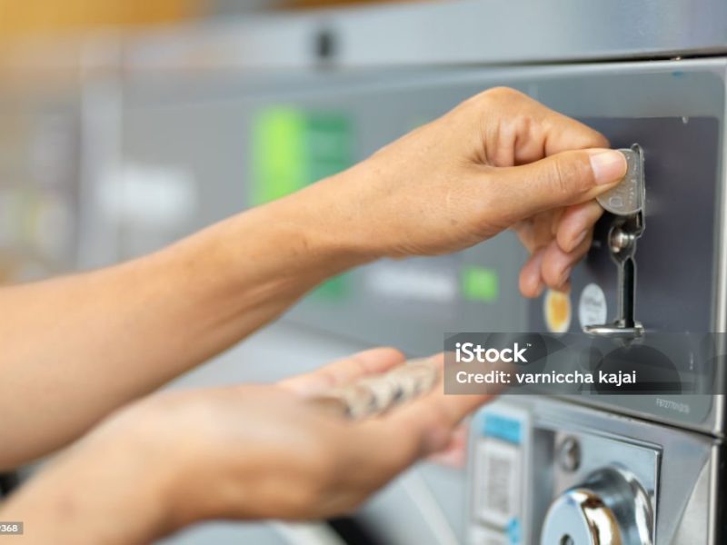Asian woman washing clothes at public coin-operated laundry